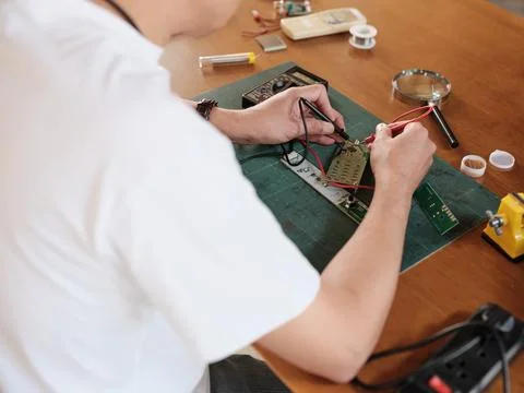 Close-up, man's hand with multimeter tool, circuit board voltage test. Stock Photos
