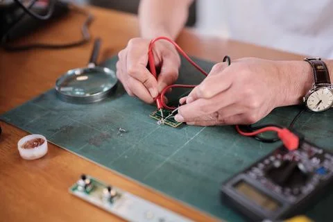 Close-up, man's hand with multimeter tool, circuit board voltage test. Stock-Fotos