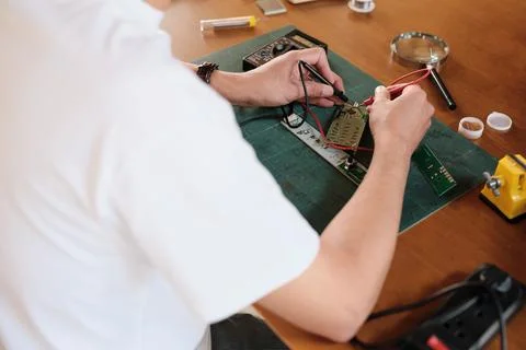 Close-up, man's hand with multimeter tool, circuit board voltage test. Фото