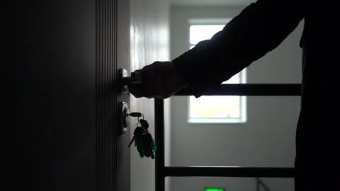 Close-up of a man's hand opening the front door to a house with a key, dark Stock Footage 254427132