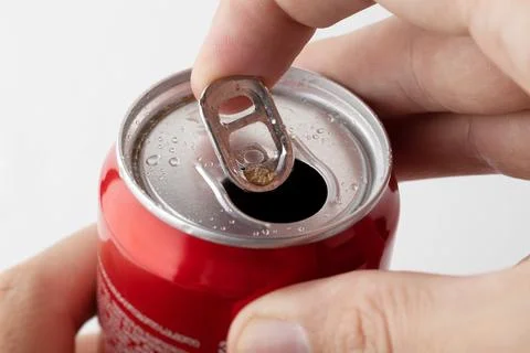 Close-up of a man's hand opening a red can of soda on a white background. Foto stock