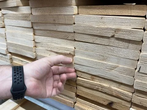 Close-up of a man's hand picking out wooden planks. Construction lumber store. Stock Photos