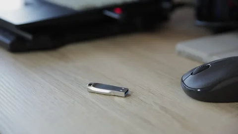Close-up of a Man's Hand Placing a Metallic USB Flash Drive on a Wooden Desk Stock Footage 331007834