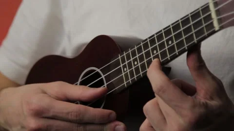 Close-up of mans hand playing ukulele in white t-shirt Stock Footage 149596474