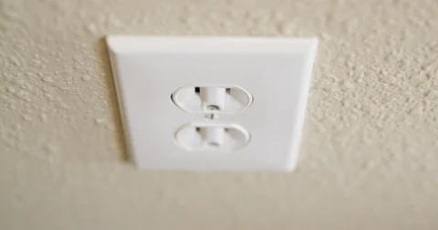Close Up of Man's Hand Plugging Cord Into Electrical Outlet Then Stock Footage 105999186