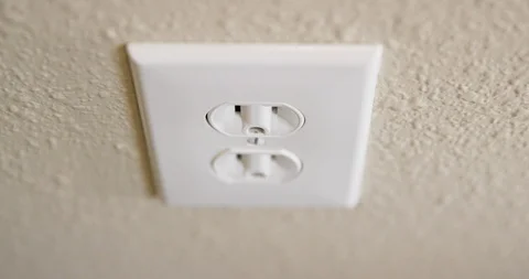Close Up of Man's Hand Plugging Cord Into Electrical Outlet Then Stock Footage 105999349