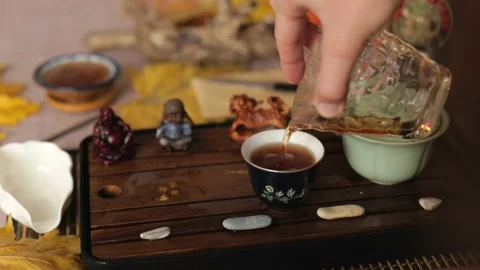 Close-up. man's hand pours Chinese tea from a glass cup into a bowl Stock Footage 220536980