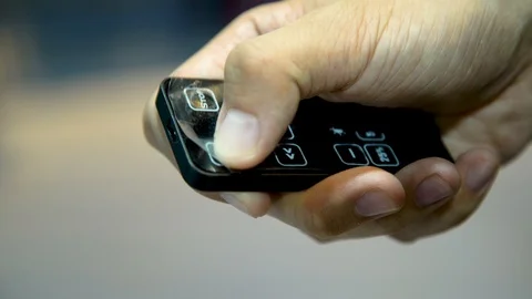 A close up of a man's hand pressing buttons on a small remote control Stock Footage 96225573