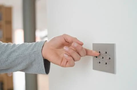 Close-up of a man's hand pressing light switch on a wall Stock Photos