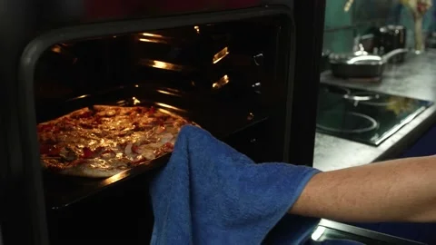 Close-up of a man's hand pulling a pizza out of the oven. Stock Footage 211815829