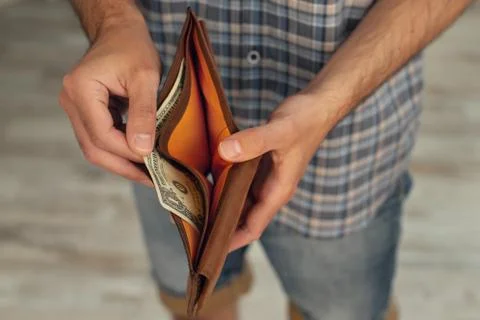 A close-up of a man's hand pulls out a 1 US dollar bill in his wallet Stock Photos