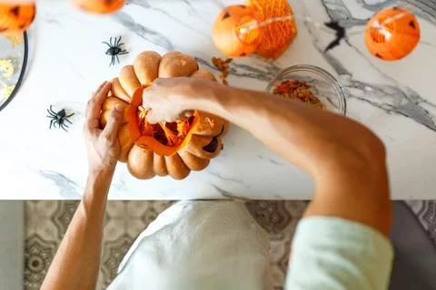 A close up of man's hand pulls seeds and fibrous material from a pumpkin before Foto stock