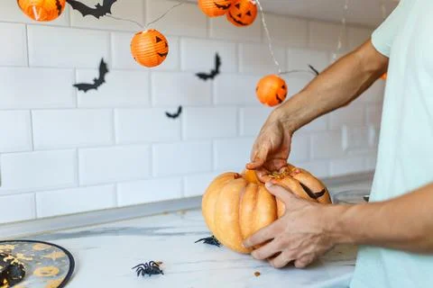 A close up of man's hand pulls seeds and fibrous material from a pumpkin before Stock Photos