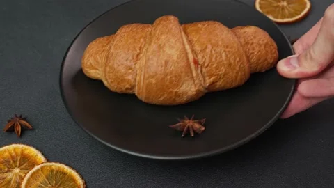 Close-up of a man's Hand Putting up a black Plate with a Croissant Stock Footage 237313433