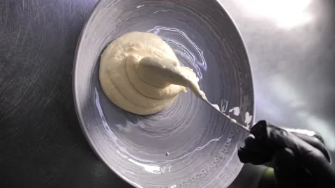 Close-up of a man's hand putting mashed potatoes with a spoon in a dish. 動画素材 231856657