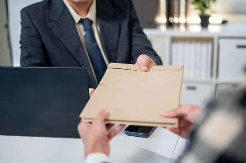 Close up of a man's hand receiving document envelope from a boss at working.. Stock Photos