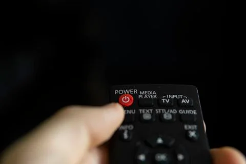 Close up on a man's hand with the remote control want switch on the TV and Stock Photos