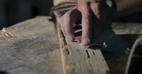 Close up of a man's hand sanding a piece of wood in dramatic lighting Stock Footage 102721389