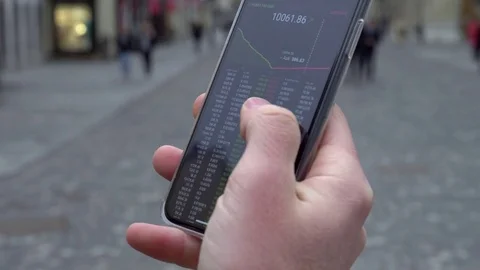 Close up - Man's hand scrolling through cryptocurrency exchange app on a phone Stock Footage 84740017