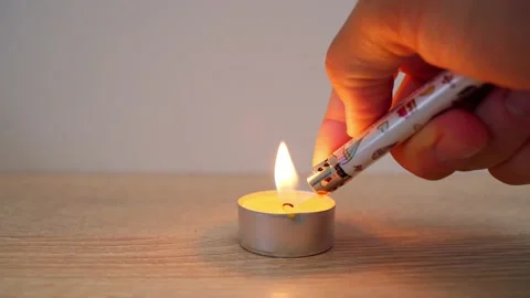 A close-up of a man's hand setting fire to an orange scented candle with a Stock Footage 203212063
