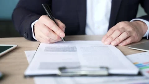 Close up of a man's hand signing documents at a desk at a workplace in a busines Stock Footage 310687018