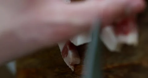 Close-up of a man's hand slicing guanciale, showcasing the rich texture and Stock Footage 309441677