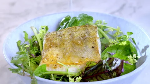 Close-up of man's hand squeezing lime juice on white fish, pike-perch zander. Video stock 275247108