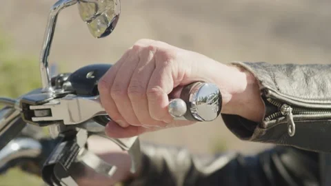 Close up of mans hand squeezing motorcycle clutch with blurry grass background Stock Footage 227449917