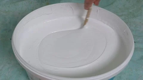 Close-up of a man's hand stirring white paint to paint the walls indoors. Stock Footage 267532817
