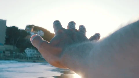 Close up mans hand sun flaring on windy beach during sunset hour Stock Footage 100262208