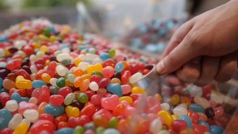 Close-up of man's hand taking colourful candies with scoop. Box with many Stock-Footage 122847954