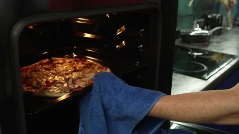 Close-up of a man's hand taking out a pizza from an electric oven in the kitchen Stock Footage 221607299