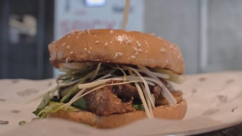 Close-up of a man's hand taking a plate with a juicy burger from a wooden bar Stock Footage 115634089