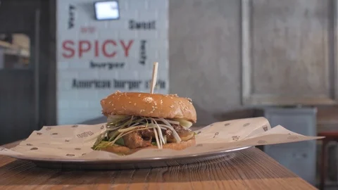 Close-up of a man's hand taking a plate with a juicy burger from a wooden bar.4k 動画素材 115634221