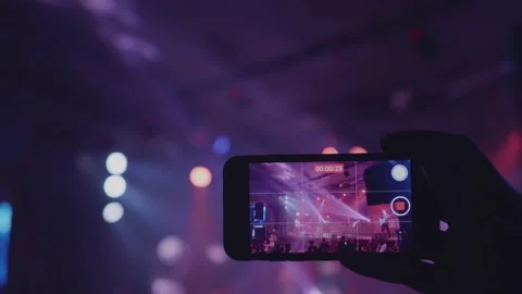 A close-up of a man's hand is taking video for a music band performing on stage. Stock Footage 145872960