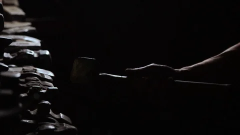 Close-up of a man's hand throws a hammer and rotates it on a dark background in Stock Footage 89290381