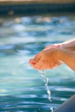 Close-up of a man's hand touching the water of the swimming pool Stock Photos