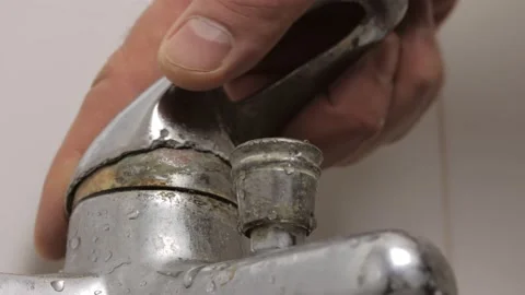 Close-up of a man's hand turning the broken lever of a water faucet Stock Footage 169235533