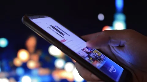 Close-up man's hand using amazon shopping app on a night city background Video stock 204797266