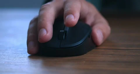 Close-up of a man's hand using a black computer mouse at a wooden table. Closeup Stock Footage 230896400