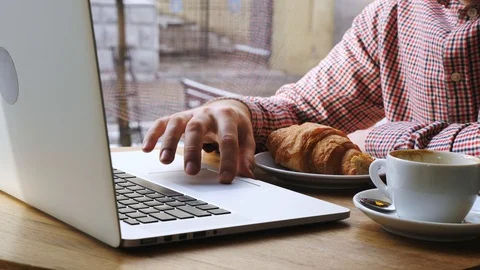 Close-up of mans hand using notebook.On the table are coffee and croissant. Stock Footage 86567378