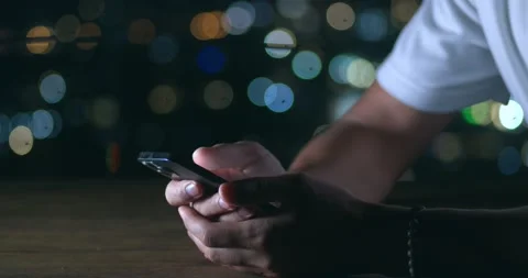 Close up of man's hand using phone at night time on city lights background. Male Stock-Footage 237984779