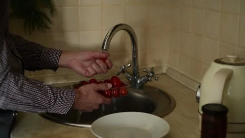 A close-up of a man's hand washing cherry tomatoes in a sink. Vídeos de archivo 318476996