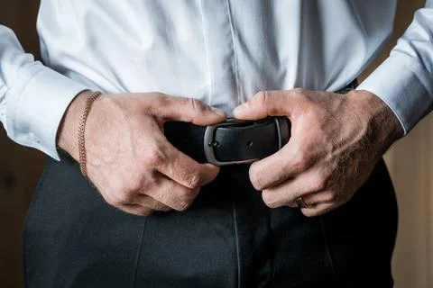 Close-Up of a Man's Hands Adjusting a Black Leather Belt Over Formal Attire Stock Photos