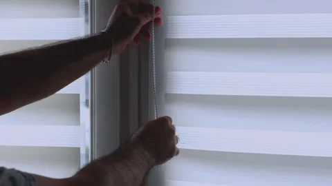 Close-up of a man's hands adjusting white zebra roller blinds on a window 스톡 동영상 336010269