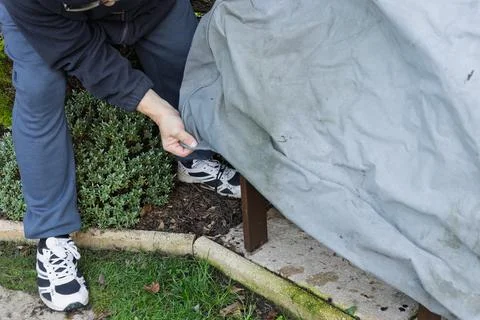Close up of mans hands adjusting winter cover on garden furniture Stock-Fotos