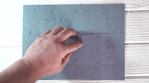 Close-up of Man's Hands Assembling Jigsaw Puzzle on Table. Stock Footage 329929529