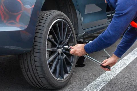 Close up mans hands changing a wheel using screwdriver. Replacing winter and  Stock Photos