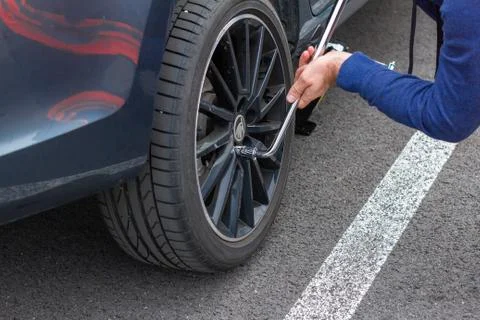 Close up mans hands changing a wheel using screwdriver. Replacing winter and  Stock Photos