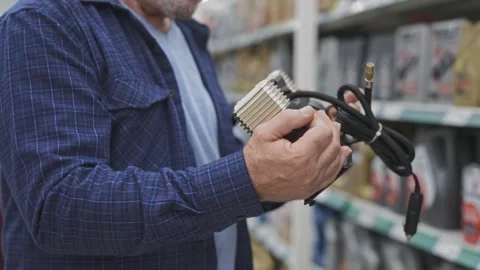 Close-up of a man's hands choosing a car compressor in an auto shop. An elderly Stock Footage 250197215
